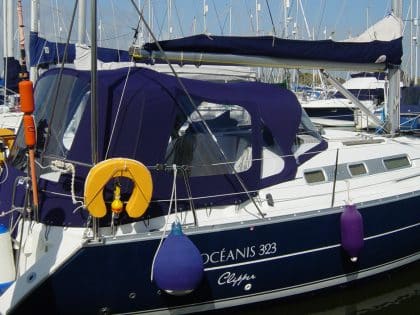 Cockpit enclosure for Beneteau Oceanis 323 with Tecsew Sprayhood Recover Type 2, featuring Sunbrella fabric and clear windows.