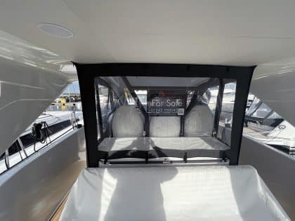 Jeanneau DB 37 with a full 3-part cockpit enclosure, showing enclosed forward and aft seating areas and clear side decks.