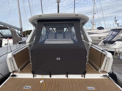 Jeanneau DB 37 with a full 3-part cockpit enclosure, showing enclosed forward and aft seating areas and clear side decks.